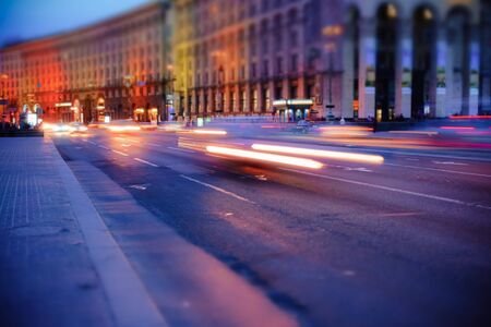 Night city street with approaching cars on the road, close up view from asphalt levelの写真素材