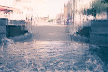 Rain water drops on window glasses surface with urban city life backgroundの写真素材
