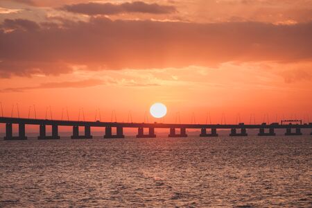 Orange sunset over the bridge silhouette. Ocean hrizon sunny landscapeの写真素材