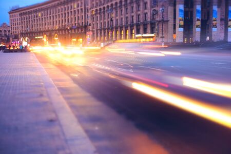 Night city street with approaching cars on the road, close up view from asphalt levelの写真素材