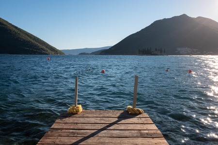 Wooden pier at the blue water of Kotor bay. Exit to the Adriatic sea. Montenegro