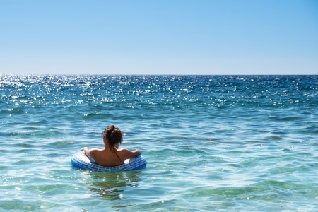 Beautiful young woman with inflatable ring relaxing in the sea.の写真素材