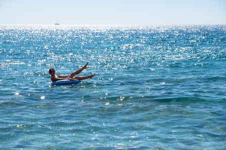 Beautiful young woman with inflatable ring relaxing in the sea.