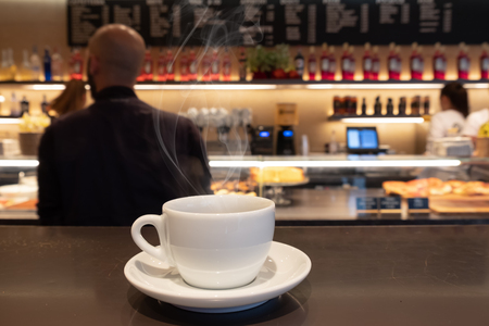 Coffee drink on wooden table with blur cafeteria as backgroundの写真素材
