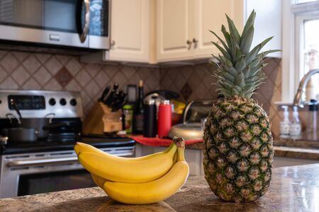 Interior of a kitchen with a bunch of bananas and pineapple on the foregroundの写真素材