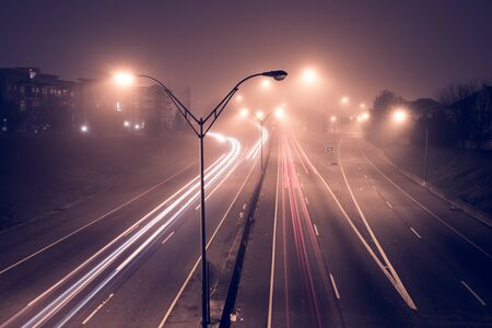 Highway at foggy night with bright trails of light from incoming and outgoing traffic....