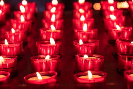 Red candles glowing in the dark. Taken in religious environmentの写真素材