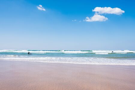 back view of unidentified man with surf board in blue ocean water. Summer beach panoramic viewの写真素材