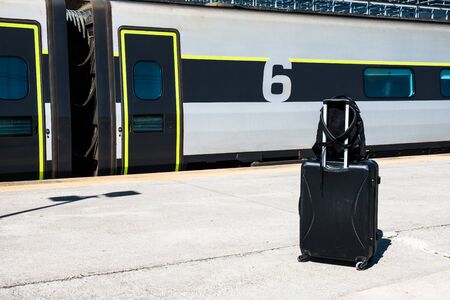 Backpack and suitcase with wheels at the train station. Baggage while waiting for the train. Travel...