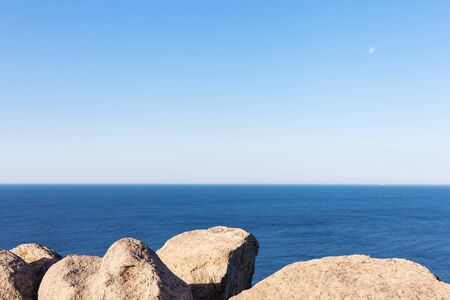 Stones, rocks, blue ocean water and sky horizon background. Nature abstract background
