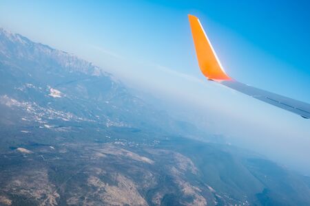 Airplane wings in the blue sky and a mountains view scene. Travel and adventure.の写真素材