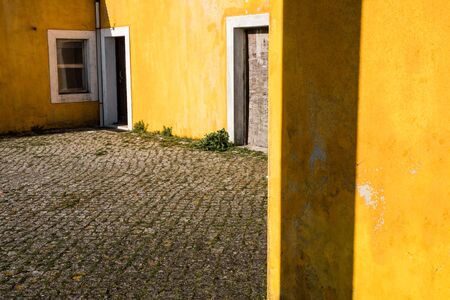 Outside view of deserted house with old and grungy yellow wall, window and worn door. Abandoned place .の写真素材