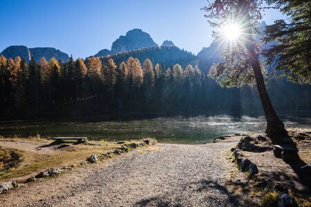 Lake with reflection of mountains at sunrise in autumn in Dolomites, Italy. Landscape with Antorno lake, blue fog over the water, trees with orange leaves and high rocks in fall. Colorful forestの写真素材