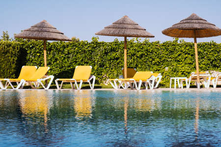 Beautiful tropical beach front hotel resort with swimming pool, sun-loungers and palm trees during a warm sunny day, paradise destination for vacationsのeditorial素材