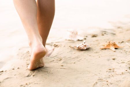 Woman walking on sand beach leaving footprints in the sandの写真素材