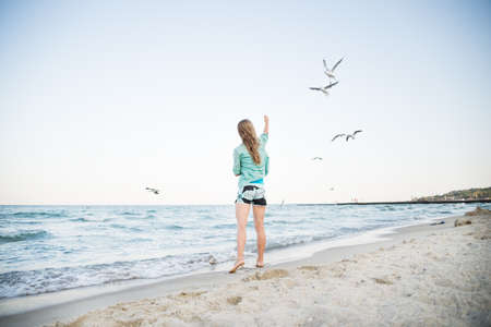 Young Girl at Beach are Feeding Seagullsの写真素材