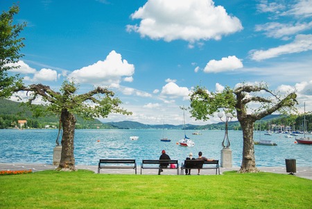 People sit on a bench at the lake Whatersee in Austriaの写真素材