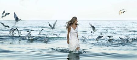 beautiful woman and seaguls on the beachの写真素材