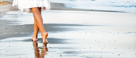 Woman walking on sand beachの写真素材