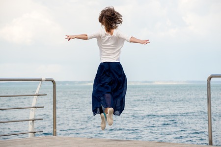 Happy young woman jumping on the beachの写真素材
