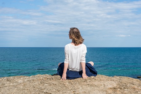 Beautiful blonde woman sitting at the beachの写真素材