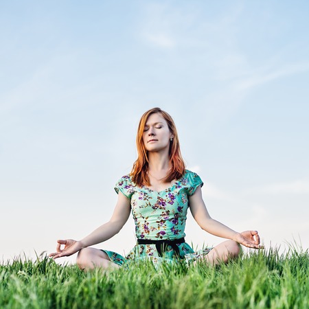 Pretty woman meditate sitting on the grassの写真素材