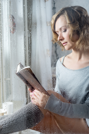 Portrait of Young woman reading throw the rain dropsの写真素材