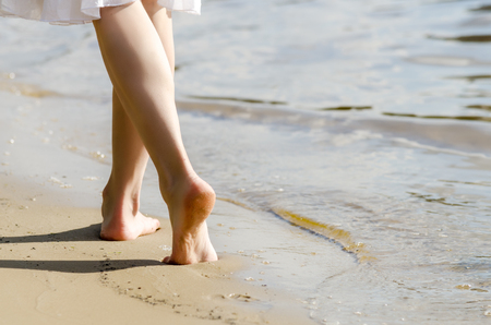 Woman walking on sand beach leaving footprints in the sandの写真素材
