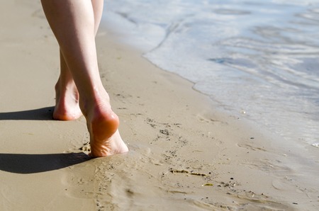 Woman walking on sand beach leaving footprints in the sandの写真素材