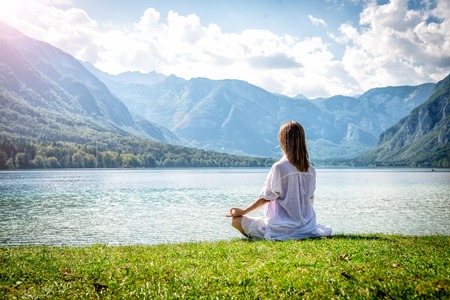 Woman meditating at the lakeの写真素材