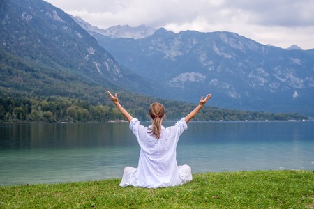 Woman meditating at the lakeの写真素材