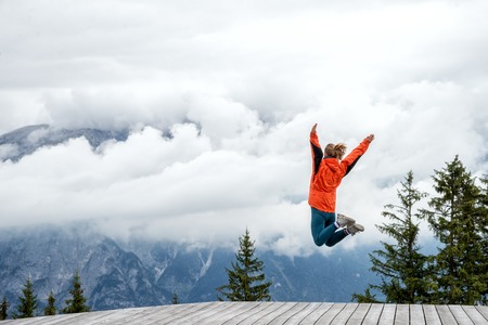 young woman jumping on top of the mountain