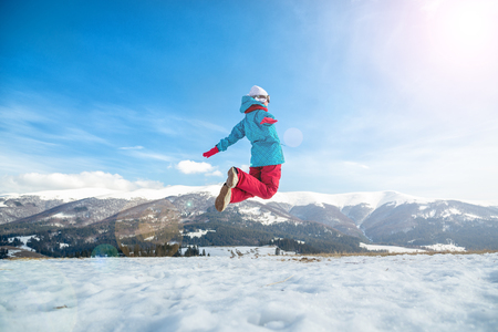young snowboarder woman jumping over the slope in winterの写真素材