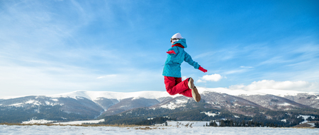young snowboarder woman jumping over the slope in winterの写真素材