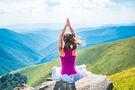 Young woman meditate on the top of mountainの写真素材