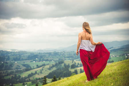 Woman in red at the green fields of Mountainsの写真素材