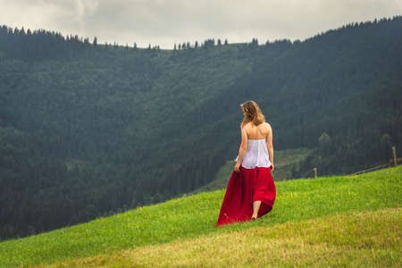 Woman in red at the green fields of Mountainsの写真素材