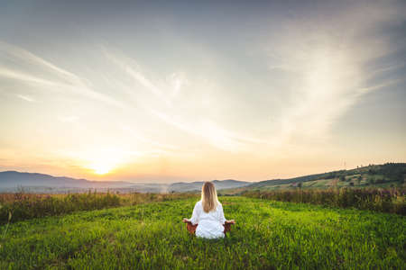 Woman doing yoga on the green grass at the mountain. Carpathiansの写真素材