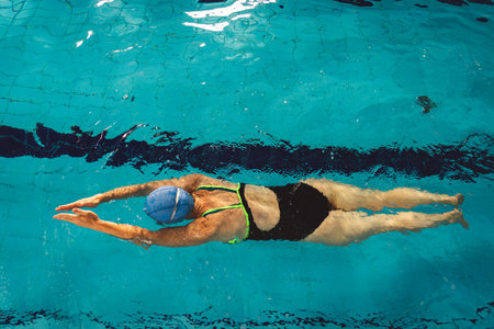 Woman swimming with swimming hat and swimsuit in swimming poolの写真素材