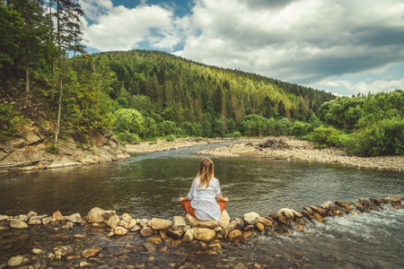 Woman doing yoga on the stone at the mountain river. Carpathiansの写真素材