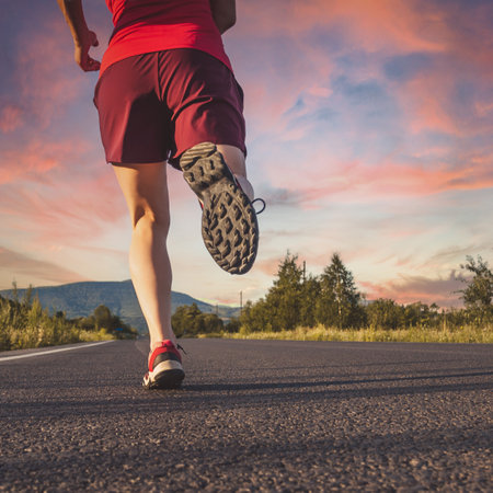 Fitness blonde woman running on the asphalt road at the mountainsの写真素材