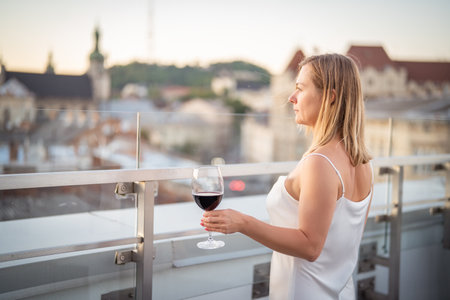 Young woman with a glass of red wine on the terrace.の写真素材