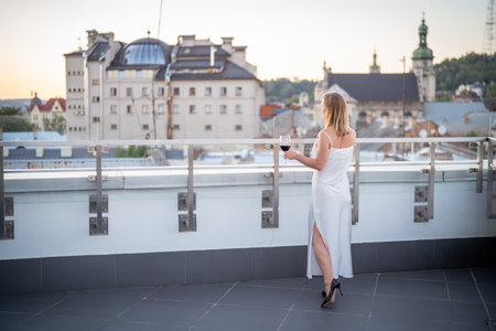 Beautiful woman with a glass of red wine on the terraceの写真素材