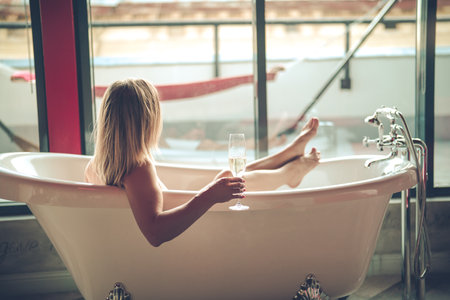 Close up of a woman holding glass of wine in bathtubの写真素材
