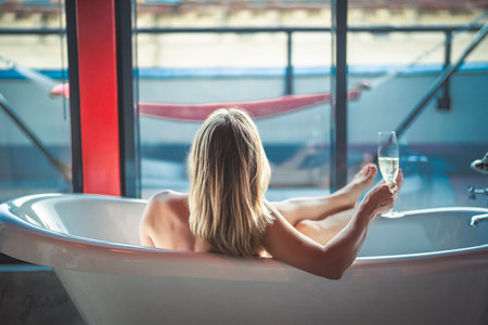 Close up of a woman holding glass of wine in bathtubの写真素材