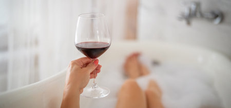 Close-up of female legs with red shoes and glass of wineの写真素材
