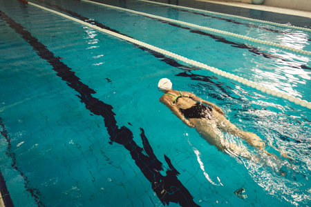 Woman swimming with swimming hat and swimsuit in swimming poolの写真素材