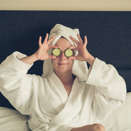 young woman getting eye nature treatment by cucumber at luxury spa resort. Wellness and healing concept.の写真素材