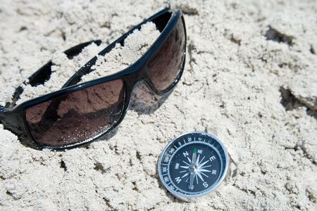 Sunglasses and compass in the sandの写真素材