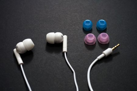 White earbuds and spare parts on a dark backgroundの写真素材